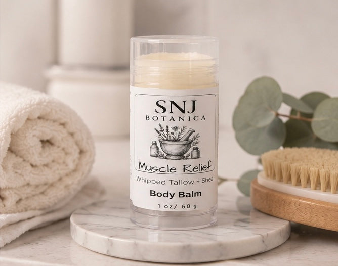 Body balm stick with SNJ Botanica label on a marble surface with bath accessories.