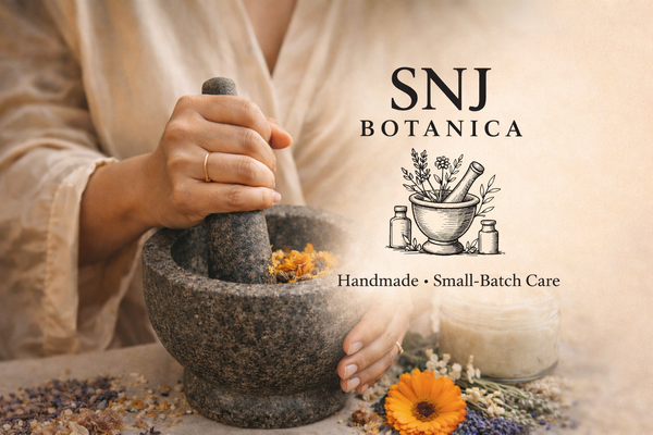 Herbs and showers surrounding a mortar and pestle. A woman’s hands grinding herbs in a mortar. 