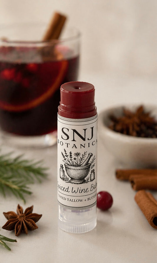 Bottle of SNJ Botanics lip balm with a glass of red wine and spices in the background