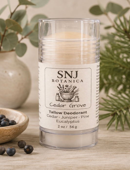 Candle with SNJ Botanica label on a wooden surface with greenery in the background