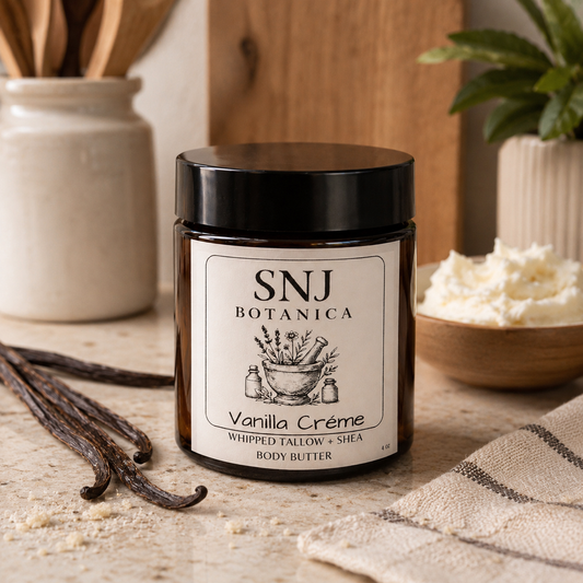 SNJ Botanica Vanilla Crème body butter jar on a wooden surface with vanilla beans and a plant in the background.