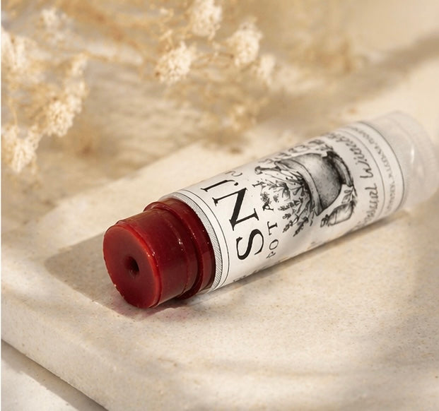 Lip balm tube with visible branding on a textured surface