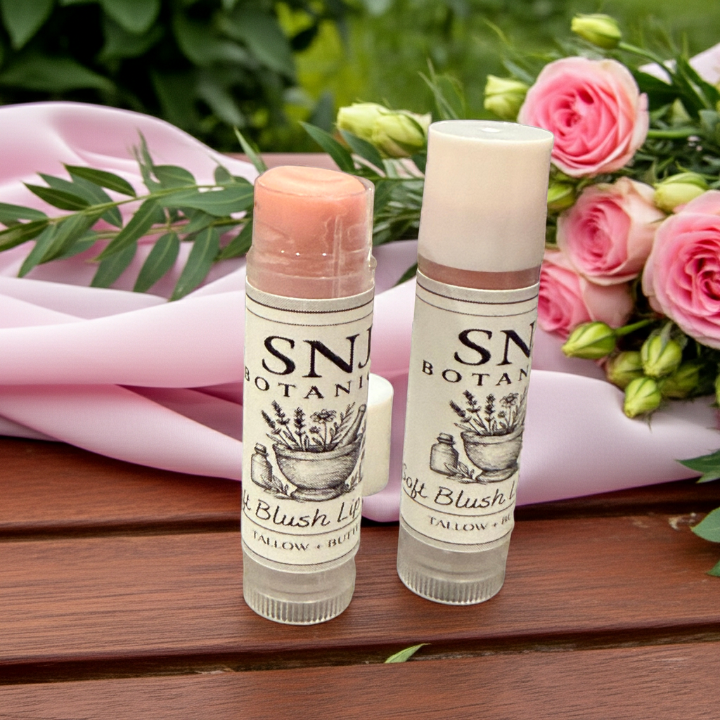 Two lip balms with 'SNJ Botan' branding on a wooden surface with flowers in the background.